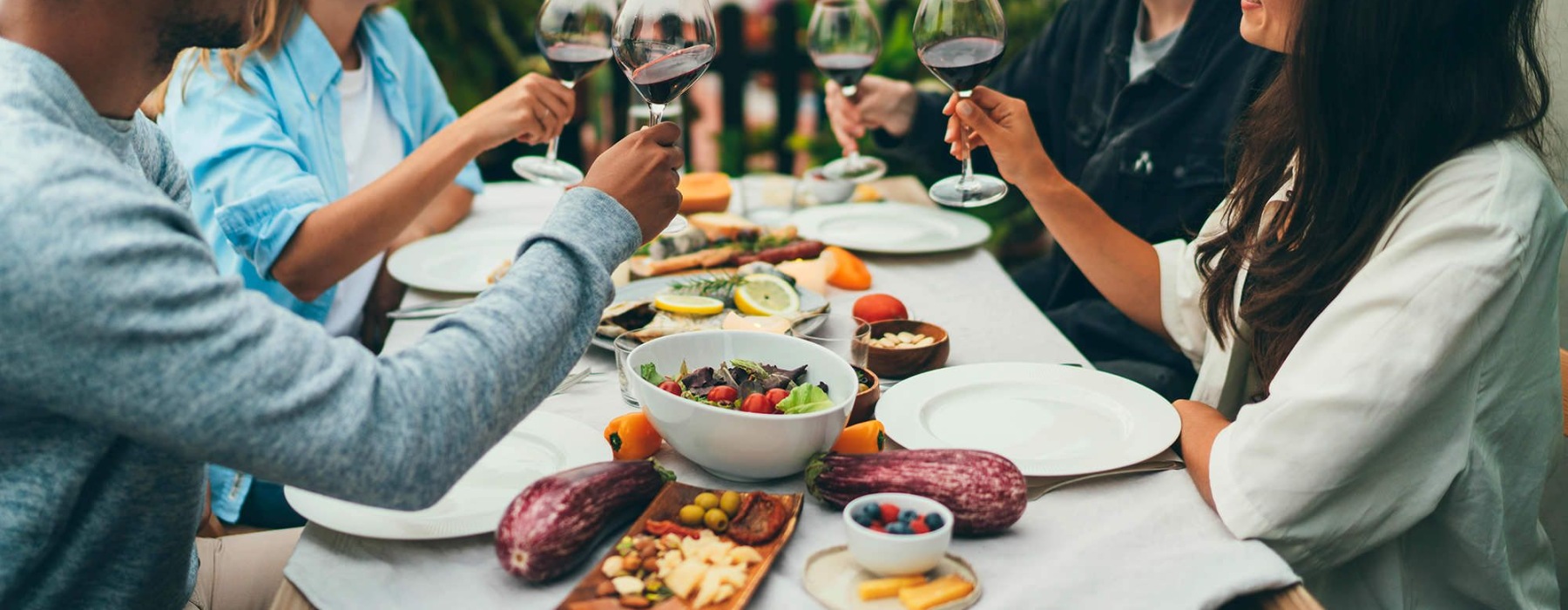 people sitting at a table with food and wine